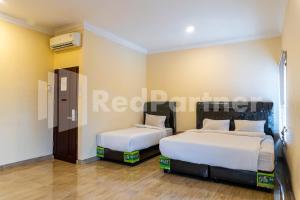棉兰Adam Malik Guesthouse near Regale ICC Medan Mitra RedDoorz的一间卧室,配有两张床