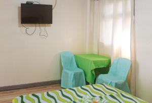 达沃市IDMAT INN的客房设有2把蓝色椅子、一张绿桌和电视。