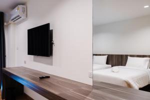 合艾JS HOTEL的一间卧室配有一张床,墙上配有电视