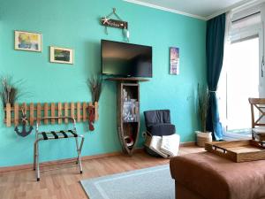 韦斯特兰13-18, sehr Strandnah, im Herzen Westerlands, Westbalkon, 1 Zi的客厅设有蓝色墙壁上的平面电视。