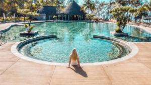 贝隆布尔毛里求斯海滩度假村的坐在游泳池前的女人