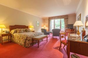卢顿卢顿胡酒店、高尔夫球场&SPA的酒店客房,配有一张床、一张桌子和椅子