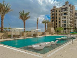 迪拜HiGuests - Charming Modern Apartment Close To The Souk in MJL的一个带白色椅子和棕榈树的游泳池