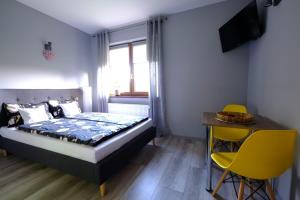 ChocieszowNoclegi Wiejski Raj的一间卧室配有一张床、一张桌子和黄色的椅子