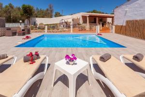 Sant RafaelVillaBlanca的游泳池设有两把椅子和一张带鲜花的桌子