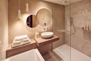 霍林赫姆Van der Valk Hotel Gorinchem的一间带水槽、浴缸和镜子的浴室