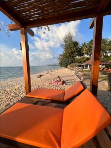 利巴诺伊Rajapruek Samui Resort - SHA Plus的沙滩上与沙滩上的人一起打着橙色长椅