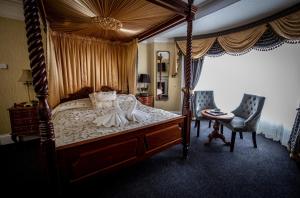 庞特佛雷特国王克罗夫特酒店的一间卧室配有天蓬床和桌椅