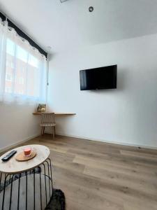 莫伯日Studio confort #2, proche Gare et commodités的一间设有桌子的房间和墙上的电视