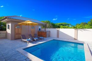 威廉斯塔德Lovely Caribbean family villa with private pool的一个带两把椅子和遮阳伞的游泳池