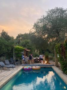 塞雷Villa Bonheur Vallespir的后院,有游泳池,人们坐在桌子旁