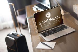 克劳利Sandman Signature London Gatwick Hotel的一张坐在木桌边的笔记本电脑