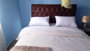奇帕塔Faigib Guest House的一张带白色床单、棕色床头板和白色枕头的床