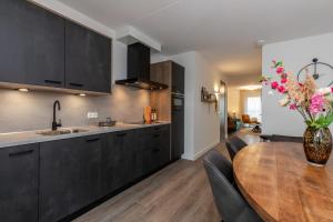 圣安娜兰Appartement Vista Maris, Havenweg 8-1, St. Annaland的厨房配有黑色橱柜和木桌