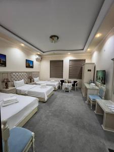 撒马尔罕Amina hotel的大房间设有几张床和桌子