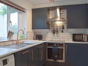 纳伯斯Castle Street Cottage的厨房配有蓝色橱柜、水槽和微波炉