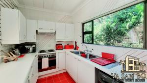 哈特比斯普特Va sabi bo, luxury family living in Hartbeespoort Dam的一间厨房,配有白色的橱柜和大窗户