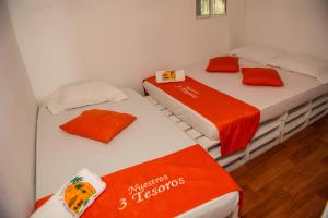 布兰卡滩Nuestros Tres Tesoros II的配有橙色和白色床单的客房内的两张床