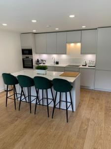 爱丁堡Lux 2 Bedroom Ground Floor Apartment的厨房配有绿色椅子和白色台面