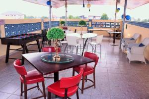 特马Lady M guest House的一间设有桌子和红色椅子的餐厅,以及种植了植物的桌子