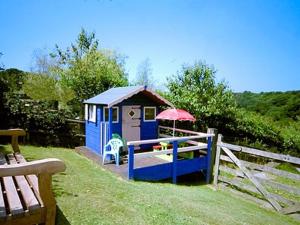 库姆马丁林地景度假屋的一个带雨伞和栅栏的小蓝色小棚