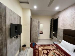 阿姆利则Shree Krishna Hotels的一间卧室配有一张床,墙上配有电视