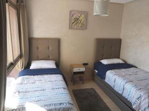 Appartement de luxe Prestigia Opale的一间卧室设有两张床、一张桌子和一个窗口