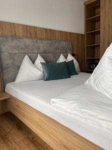 阿尔滕马克特蓬高Ski & Bike Appartements的一张带白色床单和绿色枕头的床