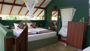 锡吉里亚Sigiri Holiday Villa的一间设有床铺的卧室,位于一个拥有绿色墙壁的房间
