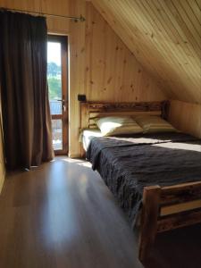 斯维季亚济Садиба ЯНА的木制客房内的一间卧室配有一张大床