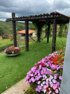 瓦尔任博尼塔Pousada Guardiã da Canastra的种满鲜花的花园和木制凉亭