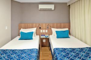 巴乌鲁Blue Tree Garden Bauru的小客房内的两张床,配有蓝色枕头