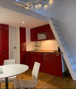 巴黎City Center Loft的厨房配有红色橱柜、白色桌子和楼梯