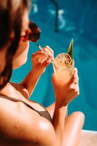 科苏梅尔Albatros Suites by Bedsfriends的坐在游泳池旁喝着饮料的女人