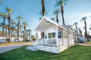 棕榈荒漠Palm Springs Camping Resort Loft Cabin 1的一座棕榈树成荫的白色小房子