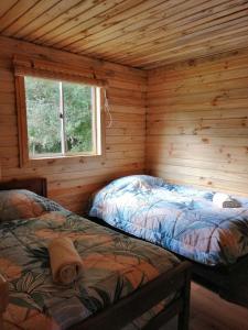 科查莫Cabaña La Troya的小木屋内一间卧室,配有两张床