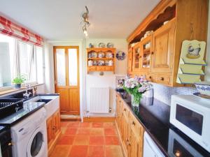 HilgayGreenbank Cottage的厨房配有木制橱柜和花瓶。