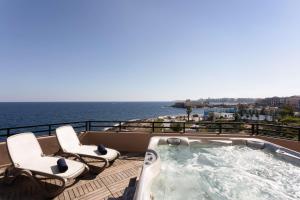 圣朱利安斯马耳他圣朱利安斯丽笙度假酒店的一个带椅子和大海的阳台的热水浴池