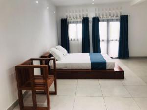图阿马西纳Le Majestic Toamasina Hotel的一间卧室配有一张带蓝色窗帘的床和一把椅子