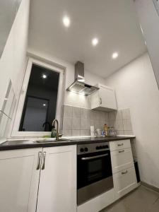 汉堡Dein Apartment的白色的厨房设有水槽和炉灶。