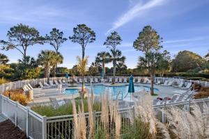 希尔顿黑德岛Ocean Dunes Villas Coligny Beach 43 S Forest Beach Dr, Hilton Head SC #111 Heated Pool Ocean View By Vacation Rental HHI LLC的度假村的游泳池,设有白色椅子和树木