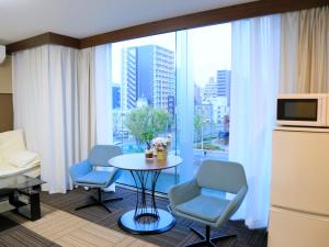 大阪Sakuragawa River Side Hotel的客房设有桌椅和大窗户。