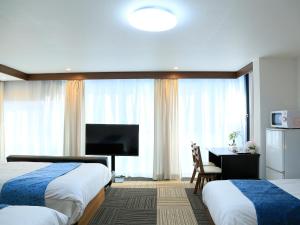 大阪Sakuragawa River Side Hotel的酒店客房设有两张床、一张桌子和一台电视。