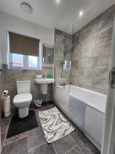 KentSpacious 3-bed Luxury Maidstone Kent Home - Wi-Fi & Parking的浴室配有卫生间、浴缸和水槽。