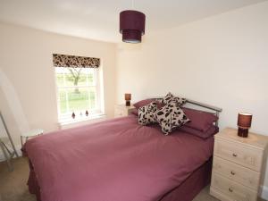 查珀尔圣伦纳兹Somer Leyton Cottage的一间卧室配有一张带紫色床单的床和窗户。