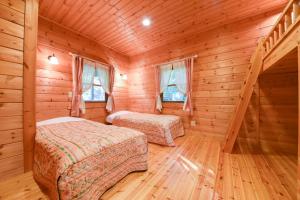 嬬恋村书林酒店的小木屋内一间卧室,配有两张床