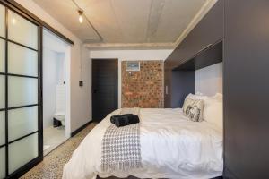 布鲁堡史特兰Manhattan On Coral Apartments的卧室配有一张白色大床和砖墙