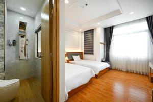 胡志明市Lotus Airport Hotel Saigon的一间卧室设有两张床、淋浴和卫生间