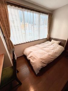 广岛lifeone club的一张位于带大窗户的房间内的床铺