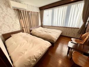 广岛lifeone club的一间卧室配有两张床、一张桌子和一把椅子
